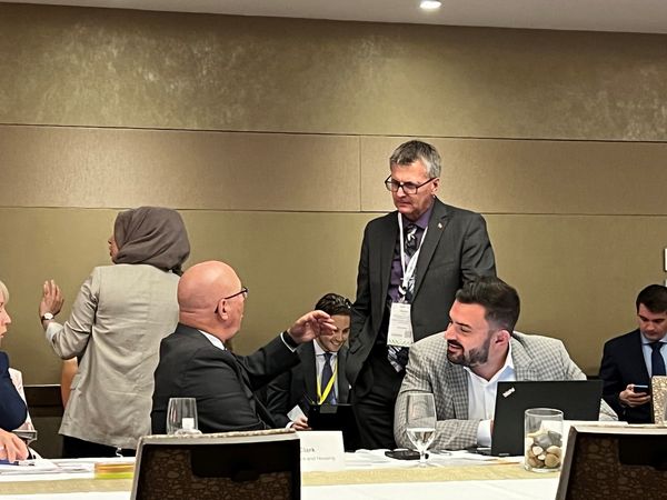 A candid photo at the AMO convention capturing MPP Holland engaged in a strategic conversation with Minister Steve Clark. The image highlights the importance of dialogue and collaboration for effective municipal leadership.