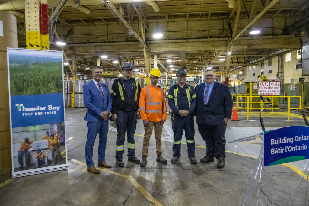 Minister Graydon Smith and MPP Kevin Holland standing with a group of mill workers for a picture after the MNRF announcement.